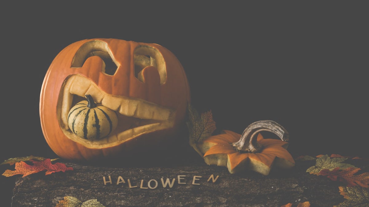 Carved jack-o'-lantern with a gourd and autumn leaves. Perfect for Halloween decor.